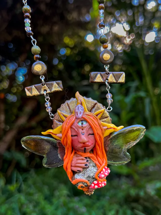 Druida solar, un ser elemental de porcelanicrón de cabello naranja, colgado de un collar de cuentas de piedra frente al bosque