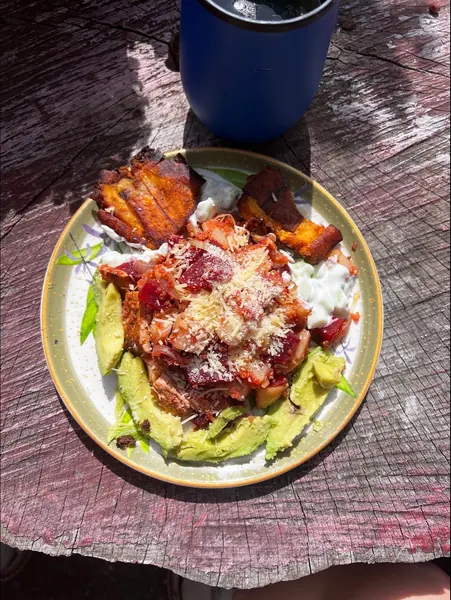 Un plato de aguacate, plátano maduro y queso sobre una mesa de madera