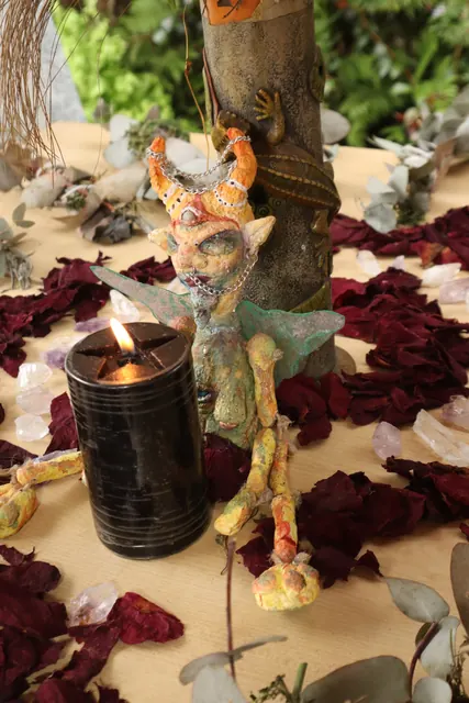 Un altar con una vela encendida y pétalos de rosa rojos